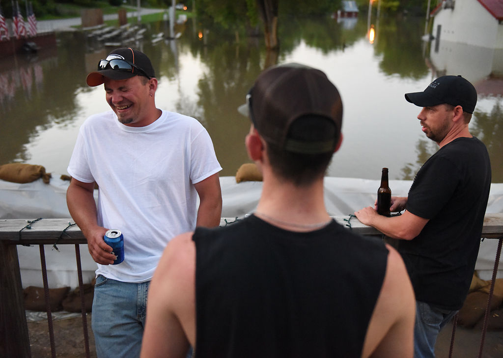 From left, Randal Hickman, Ryan Elder, and Eric Bryne enjoy a beer on the porch